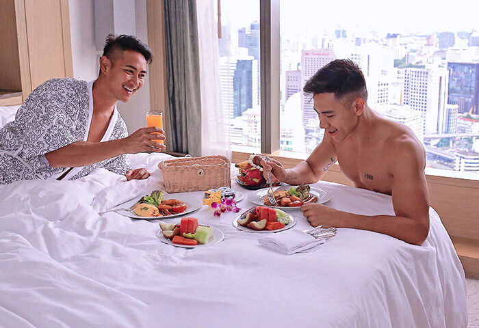 Gay-friendly Banyan Tree Bangkok hotel: Two gay men enjoy breakfast in bed with a city view. Luxury travel experience in Thailand.