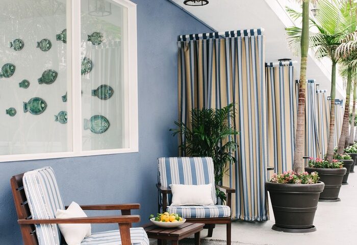 Bayside Hotel patio. Gay-friendly hotel seating area with striped chairs, table, and curtains. Palm trees add to the tropical vibe.
