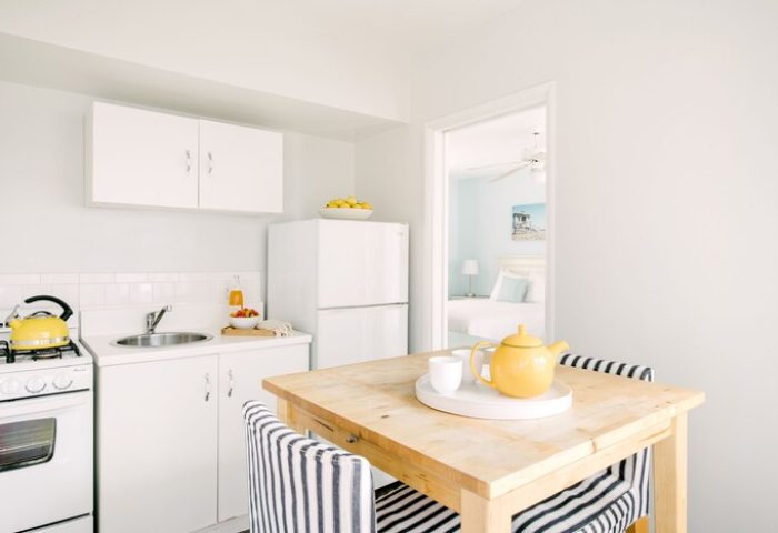 Bayside Hotel kitchenette. Gay-friendly hotel with a stove, sink, fridge, and table. Bedroom visible in the background. Perfect for gay travel.