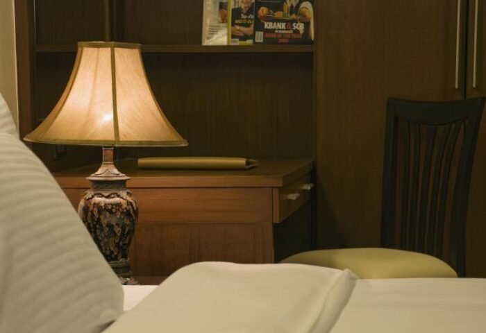 Baywalk Residence detail: Bedside lamp on a desk with magazines, chair. Gay-friendly hotel room interior, comfortable stay. Travel advice.