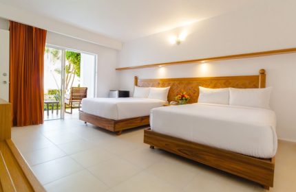 Beachscape Kin Ha Villas & Suites Cancun room. Two beds, wooden headboards, white linens. Balcony view. Gay-friendly hotel.