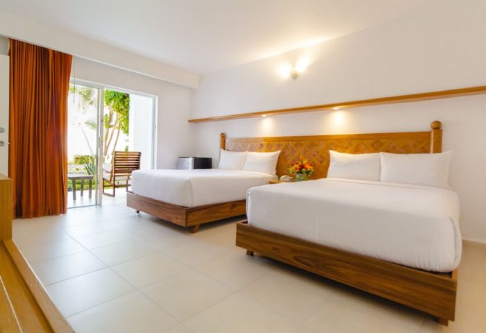 Beachscape Kin Ha Villas & Suites Cancun room. Two beds, wooden headboards, white linens. Balcony view. Gay-friendly hotel.