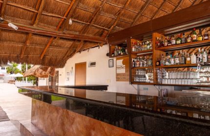 Beachscape Kin Ha Villas & Suites Cancun bar. Gay-friendly hotel with thatched roof, liquor shelves, and glasses. Ideal for gay travel.