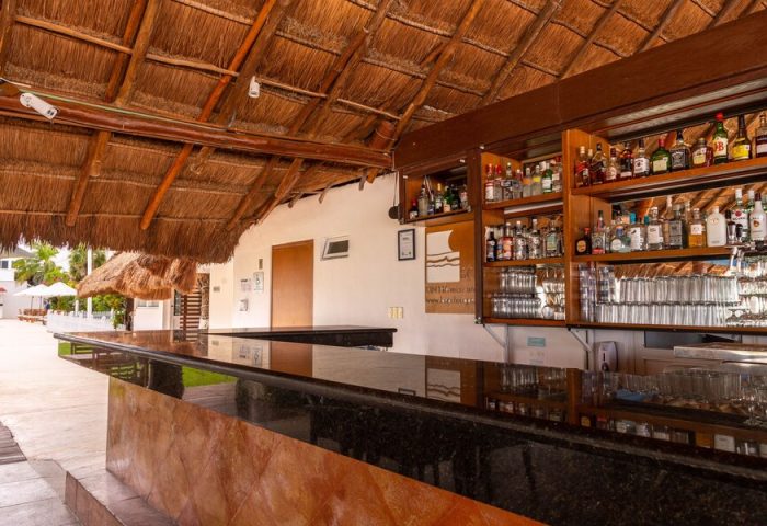 Beachscape Kin Ha Villas & Suites Cancun bar. Gay-friendly hotel with thatched roof, liquor shelves, and glasses. Ideal for gay travel.
