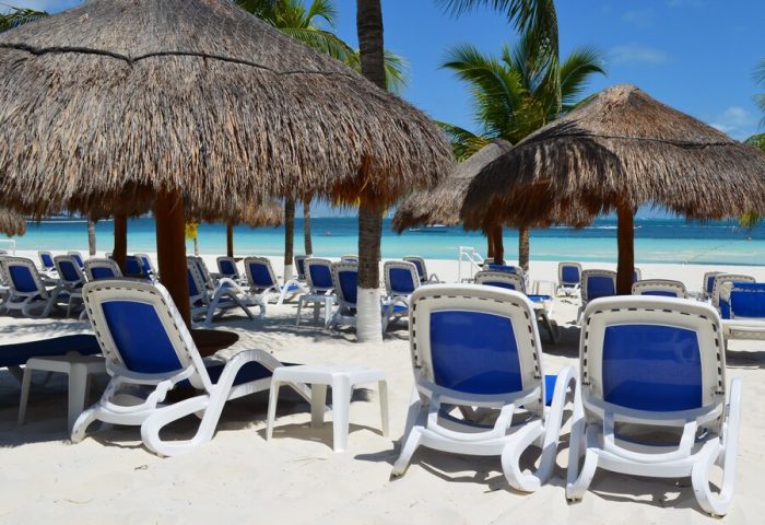 Beachscape Kin Ha Villas & Suites Cancun beach view. Gay-friendly hotel with chairs, umbrellas, white sand, & blue ocean. Perfect for gay travel.