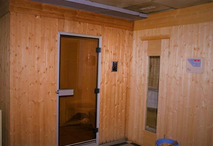Sauna room at Beijing Guoan Hotel, a gay-friendly hotel. Features wood paneling, glass door, and temperature controls. Relaxing spa for gay travelers.