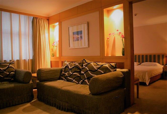 Beijing Guoan Hotel room. Gay-friendly hotel in Beijing with a sofa, bed, and warm lighting. Comfortable lodging for gay travelers.