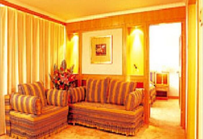 Beijing Guoan Hotel room with striped sofa, chair, and flowers. Gay-friendly hotel in Beijing, China, offers comfortable accommodations.