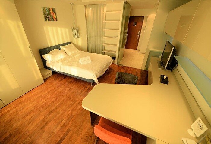 Beijing New Oriental Suites in Seasons Park Sanlitun: Modern hotel room with bed, desk, and wooden floor. Gay-friendly hotel in Beijing.