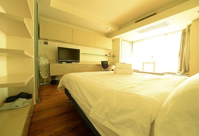 Beijing New Oriental Suites in Seasons Park Sanlitun room. Gay-friendly hotel bedroom with bed, TV, and desk. Modern design.