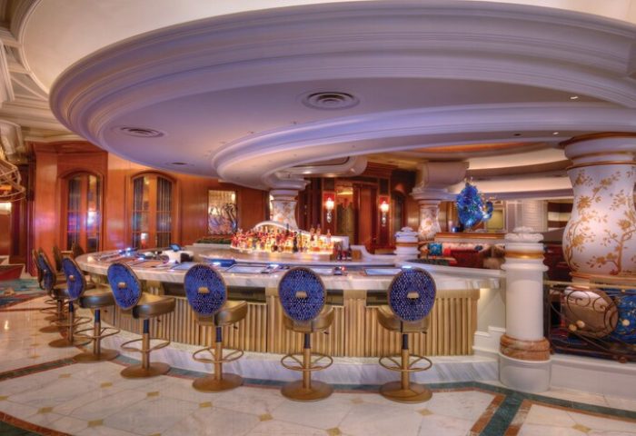 Interior of the gay-friendly Bellagio Hotel bar. The bar has a round shape and is decorated with blue chairs and marble countertops.