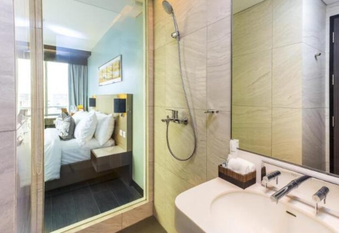 Belmont Hotel Manila bathroom and bedroom view. Gay-friendly hotel with modern shower, sink, and comfy bed. Great for gay travel in Manila.