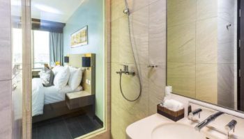 Belmont Hotel Manila bathroom and bedroom view. Gay-friendly hotel with modern shower, sink, and comfy bed. Great for gay travel in Manila.