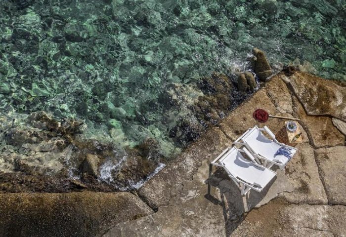 Belvedere Little Venice pied-a-terres: Gay-friendly hotel with two beach chairs on rocks by clear water. Perfect gay travel destination.