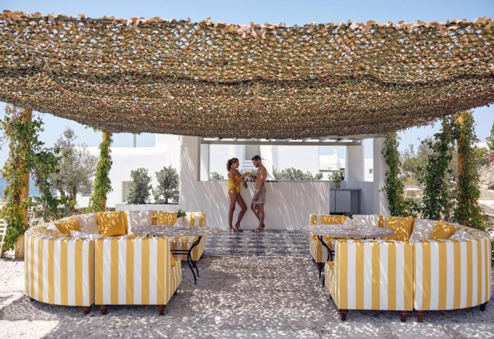 Belvedere Mykonos Hilltop Complex: Gay-friendly hotel with stylish outdoor lounge, bar, and couple enjoying drinks. Luxury gay travel.