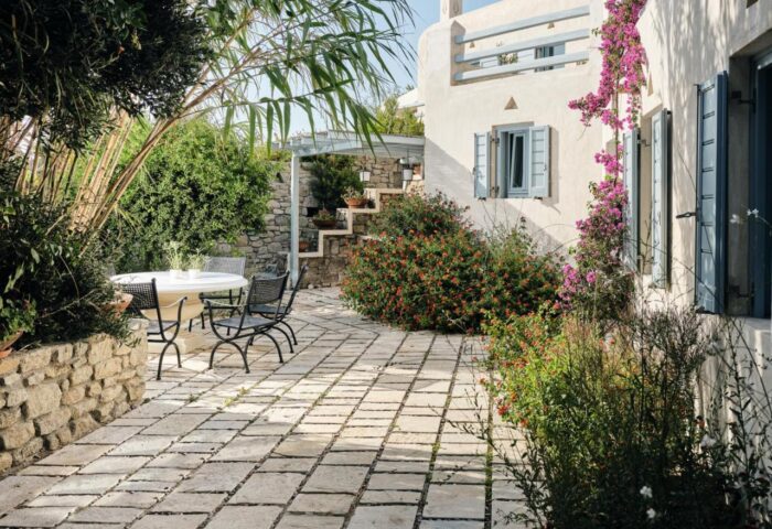 Belvedere Mykonos Waterfront Villa Suites patio. Gay-friendly hotel with outdoor dining, flowers, and stone details. Mykonos travel.