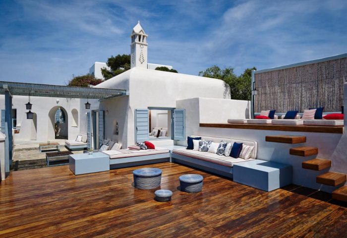 Belvedere Mykonos Waterfront Villa & Suites: Gay-friendly hotel rooftop lounge area. White walls, blue accents, wood floors, & stylish seating.