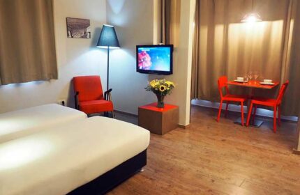 Ben Yehuda Apartments interior. Gay-friendly lodging with twin beds, TV, dining table, and modern decor. Perfect for gay travelers' comfort.