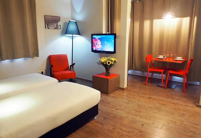 Ben Yehuda Apartments interior. Gay-friendly lodging with twin beds, TV, dining table, and modern decor. Perfect for gay travelers' comfort.