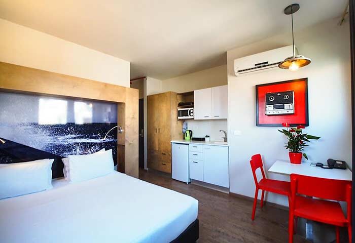 Ben Yehuda Apartments interior. Gay-friendly hotel room with bed, kitchenette, table, and chairs. Modern design for gay men's travel.