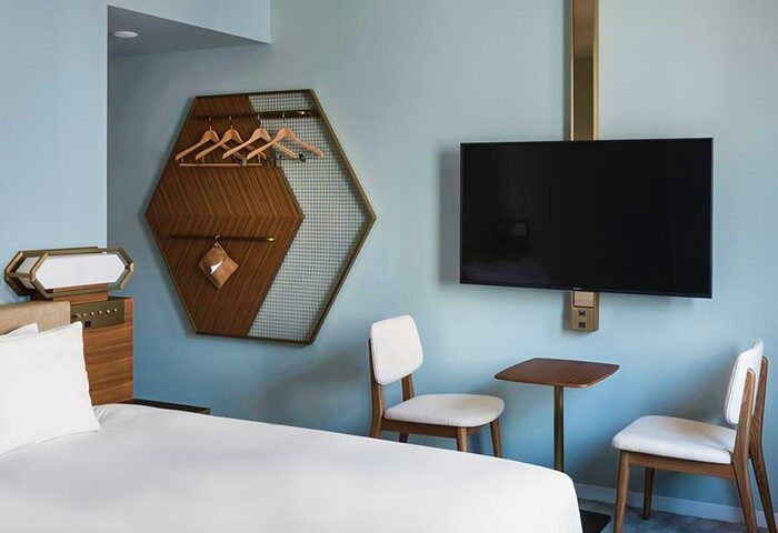 Bespoke Hotel Shinjuku room. Gay-friendly hotel design with bed, TV, chairs, and unique hexagonal wall-mounted closet with hangers. Modern, stylish.