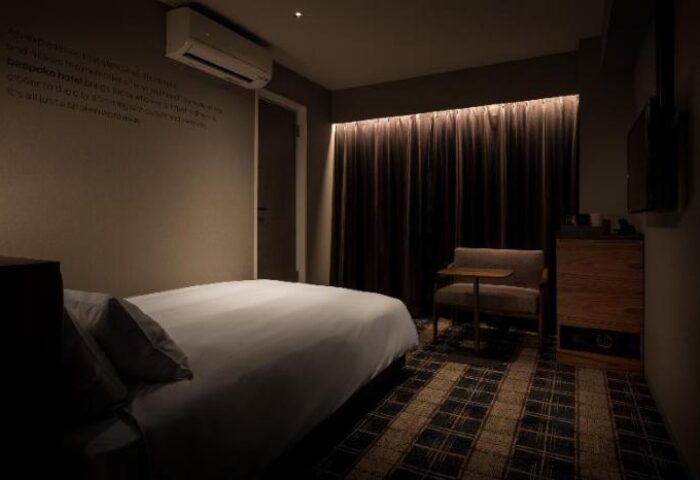 Bespoke Hotel Shinjuku room interior. Gay-friendly hotel with a bed, chair, and dark curtains. Modern design in Shinjuku, Tokyo. Japan travel.