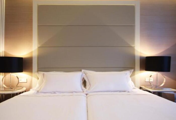 BessaHotel Liberdade bedroom. Gay-friendly hotel room with two beds, white linens, headboard, and lamps. Ideal lodging for gay travelers.