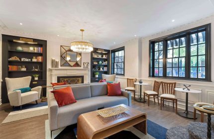 Best Western Plus Hawthorne Terrace Hotel gay-friendly suite. Living room with sofa, chairs, fireplace, & bookshelves. Stylish decor.