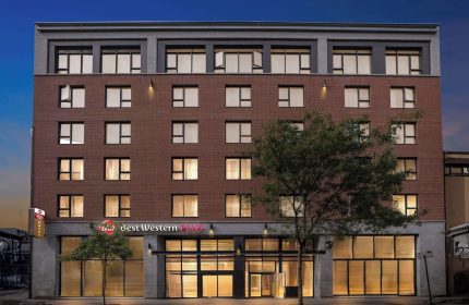 Best Western Plus Hotel Montreal, a gay-friendly hotel. Exterior view of the brick building at dusk, offering accommodations for gay travelers.