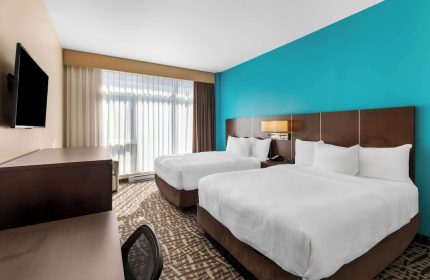 Best Western Plus Hotel Montreal guest room with two beds. Gay-friendly hotel room interior with desk, tv, and blue accent wall.