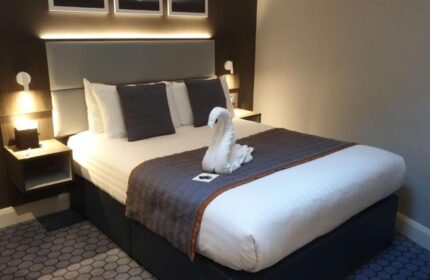 Best Western Plus Vauxhall Hotel room with swan towel art. Gay-friendly hotel with modern decor, bedside tables, and comfortable bed.