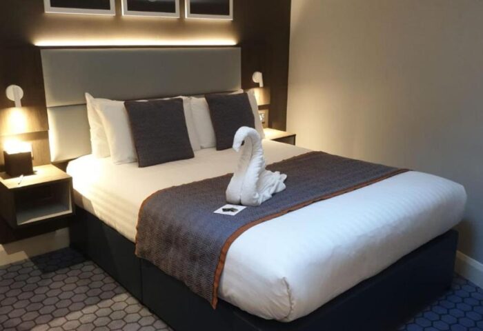Best Western Plus Vauxhall Hotel room with swan towel art. Gay-friendly hotel with modern decor, bedside tables, and comfortable bed.