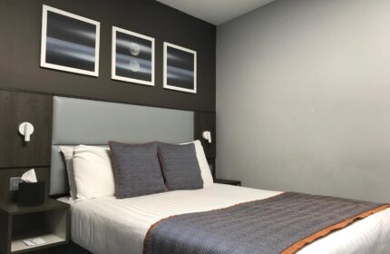 Bedroom in Best Western Plus Vauxhall Hotel, a gay-friendly hotel. Bed with gray headboard, pillows, and throw. Modern art on the dark wall.