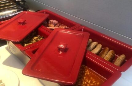 Breakfast buffet at Best Western Plus Vauxhall Hotel. Red warming trays hold sausages, beans, mushrooms, and bacon. Gay-friendly hotel.