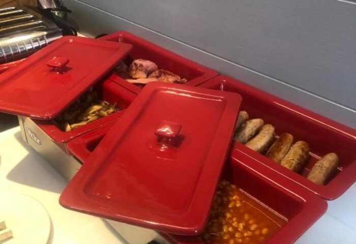 Breakfast buffet at Best Western Plus Vauxhall Hotel. Red warming trays hold sausages, beans, mushrooms, and bacon. Gay-friendly hotel.