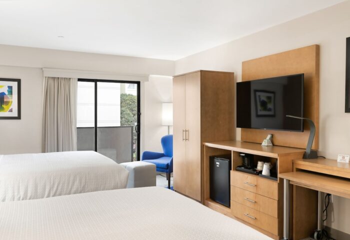 Best Western Red Coach Inn room. Gay-friendly hotel with two beds, TV, desk, balcony, and blue chair. Comfortable stay for gay travelers.