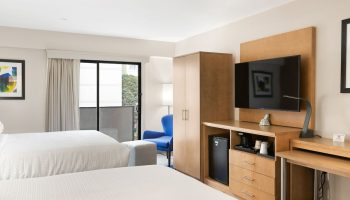 Best Western Red Coach Inn room. Gay-friendly hotel with two beds, TV, desk, balcony, and blue chair. Comfortable stay for gay travelers.