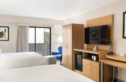 Best Western Red Coach Inn room. Gay-friendly hotel with two beds, TV, desk, balcony, and blue chair. Comfortable stay for gay travelers.