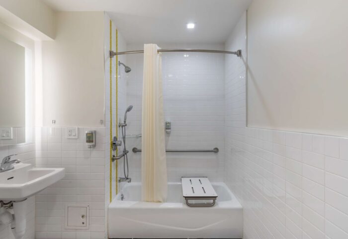Best Western Red Coach Inn gay-friendly hotel bathroom. Accessible tub with seat and handrails. White tile and shower curtain.