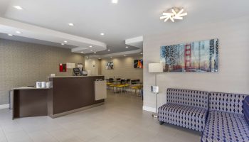 Best Western Red Coach Inn lobby. Gay-friendly hotel with modern decor, reception desk, seating area, and Golden Gate Bridge art.