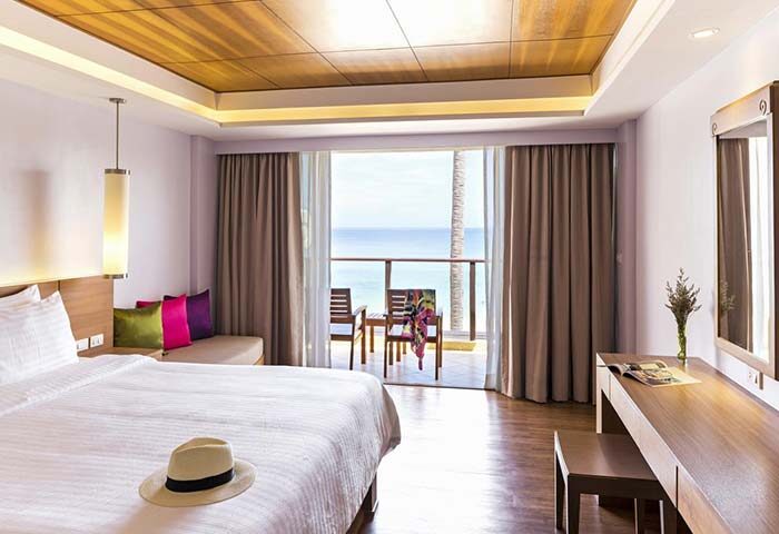 Gay-friendly Beyond Resort Karon room with balcony, ocean view, bed, and desk. Karon, Thailand hotel for gay men and LGBTQ+ travelers.