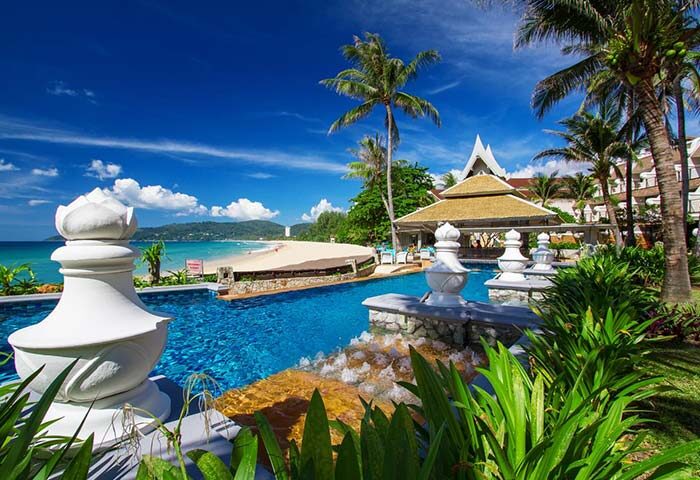Beyond Resort Karon pool view. Gay-friendly hotel in Phuket, Thailand. Tropical beach paradise with palm trees and blue sky. Karon beach resort.