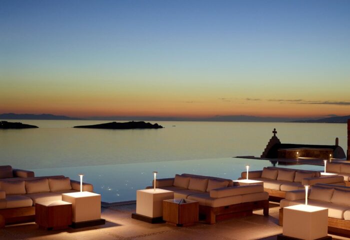Bill & Coo Suites and Lounge, a gay-friendly hotel. Infinity pool and lounge area at sunset. Mykonos luxury travel for gay men.