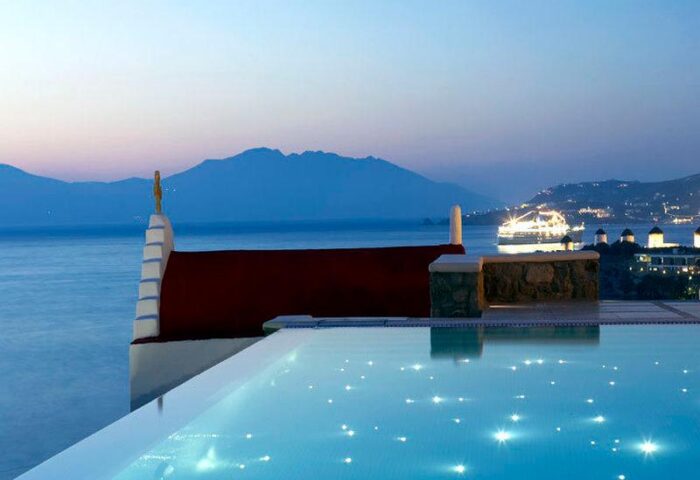 Bill & Coo Suites and Lounge infinity pool overlooking the Aegean Sea. Gay-friendly hotel in Mykonos at dusk.
