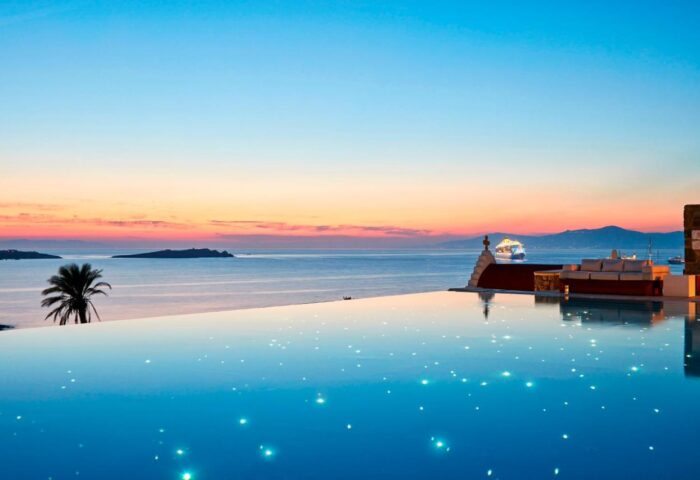 Infinity pool at Bill & Coo Suites, a gay-friendly hotel in Mykonos. Sunset view over the Aegean Sea. Luxury travel for gay men.