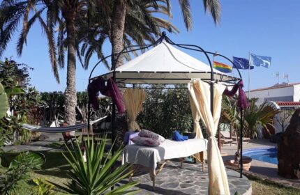 Birdcage Gay Men's Resort: Outdoor massage gazebo with rainbow flag. Gay-friendly hotel for gay men's travel and lifestyle. Palm trees.