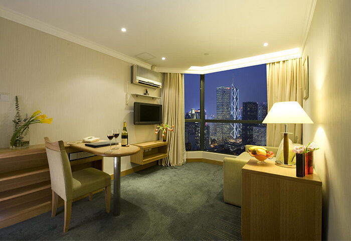 Bishop Lei International House room with city view. Gay-friendly hotel in Hong Kong. Modern interior, desk, wine, and skyline.
