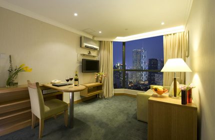 Bishop Lei International House room with city view. Gay-friendly hotel in Hong Kong. Modern interior, desk, wine, and skyline.