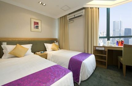 Bishop Lei International House room with two beds, desk, and city view. Gay-friendly hotel in Hong Kong for gay men travel.