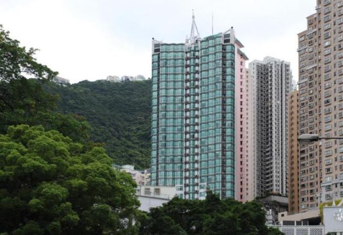 Bishop Lei International House: Gay-friendly hotel view. High-rise building with green glass facade, surrounded by other buildings and lush greenery.